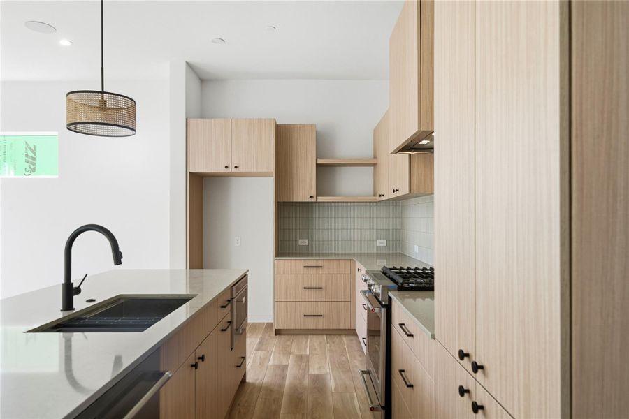 Kitchen featuring stainless steel appliances, light stone countertops, light wood-style flooring, decorative light fixtures, and recessed lighting