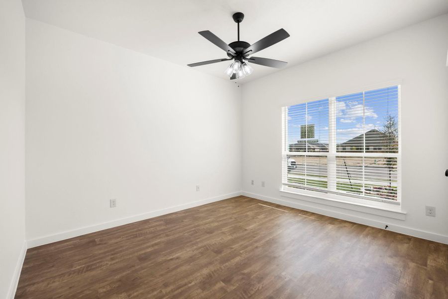 A versatile space features modern wood flooring and a large window, offering views of the neighborhood.