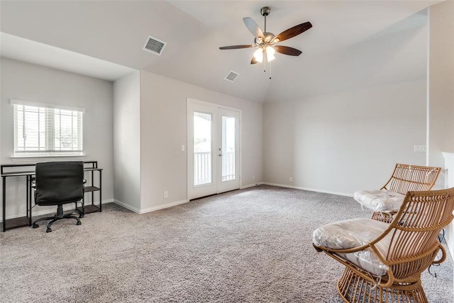 Living area featuring light carpet, ceiling fan, and plenty of natural light