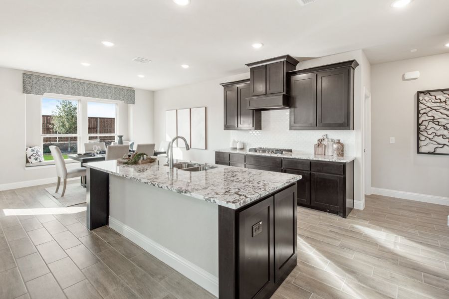 Kitchen with large granite island, dark cabinets, and tile floors open to dining area Kitchen with large granite island, dark cabinets, and tile floors open to dining area