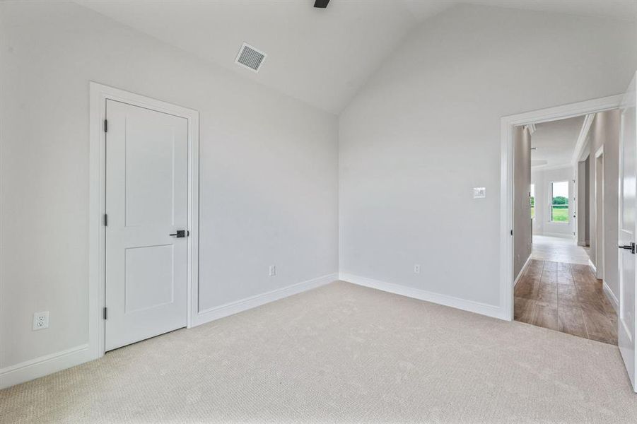 Empty room with carpet flooring, lofted ceiling, baseboards, and ceiling fan