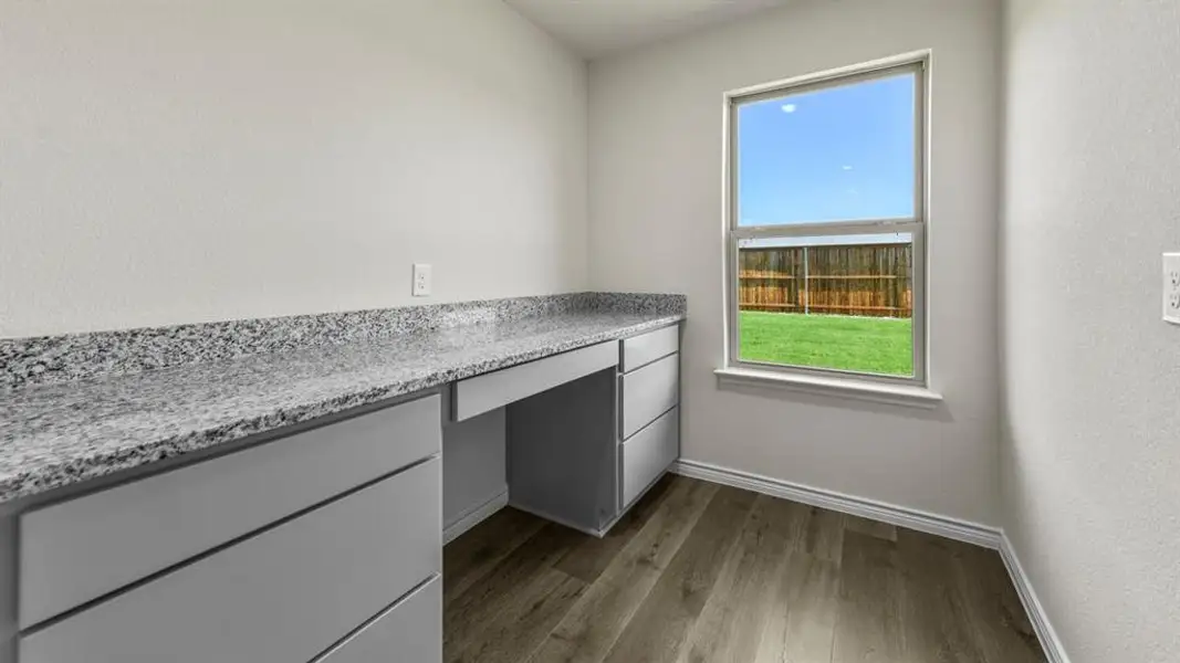 Dedicated workspace featuring an expansive countertop, integrated cabinetry, a built-in desk area, and wood-finish flooring