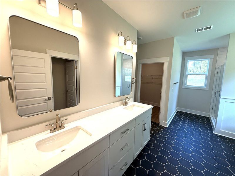 A well-lit primary bathroom featuring dual vanitie A well-lit primary bathroom featuring dual vanitie