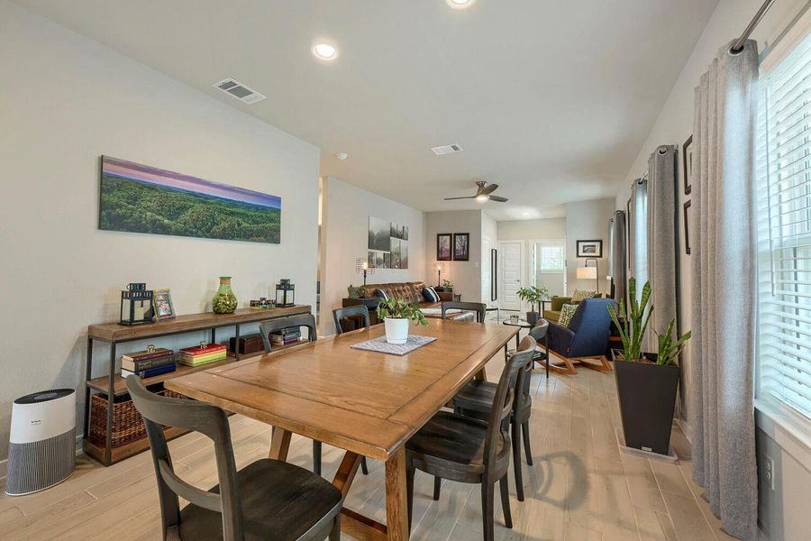 An open concept dining area features light wood flooring and connects to a welcoming living space. An open concept dining area features light wood flooring and connects to a welcoming living space.