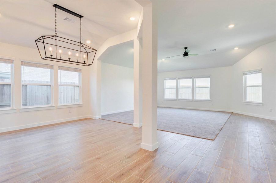 Bright, open-concept living and dining areas designed for effortless everyday living and entertaining. Wood-look tile flooring flows throughout the main living spaces, complemented by recessed lighting and high ceilings that enhance the sense of openness. The formal dining area is highlighted by a modern chandelier and large windows that bring in abundant natural light. Seamless sightlines connect the dining space to the family room, creating a functional layout ideal for gatherings.