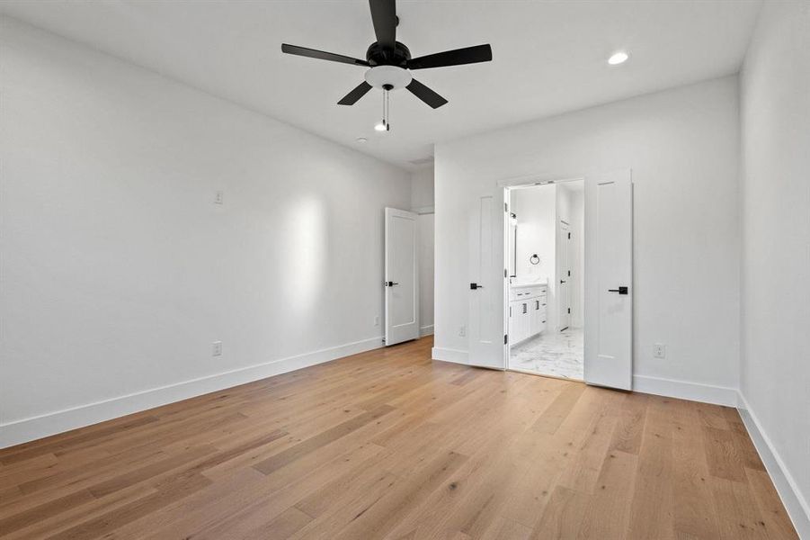 Unfurnished bedroom with light wood-style flooring, recessed lighting, ceiling fan, and ensuite bathroom