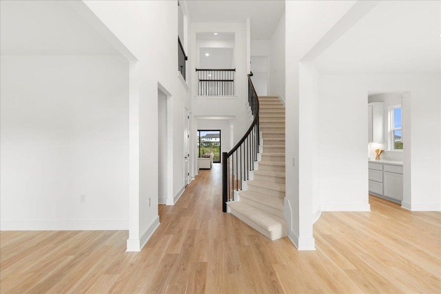 Foyer featuring a high ceiling, light wood finished floors, and stairs Foyer featuring a high ceiling, light wood finished floors, and stairs