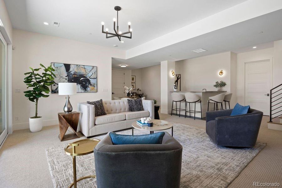 The lower-level family room offers bright walls and plush carpeting with a modern pendant light.