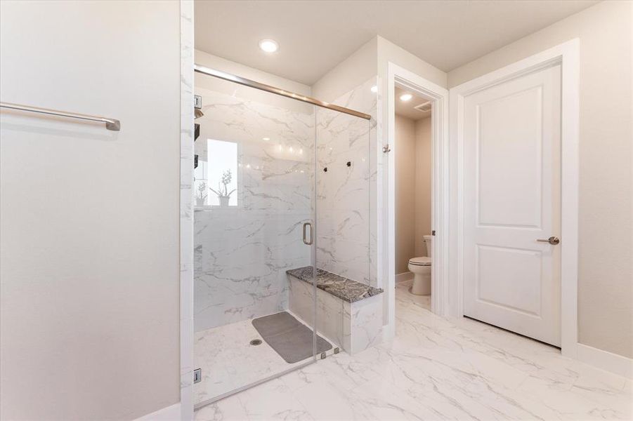 Primary bathroom shower with glass door and oversized tile