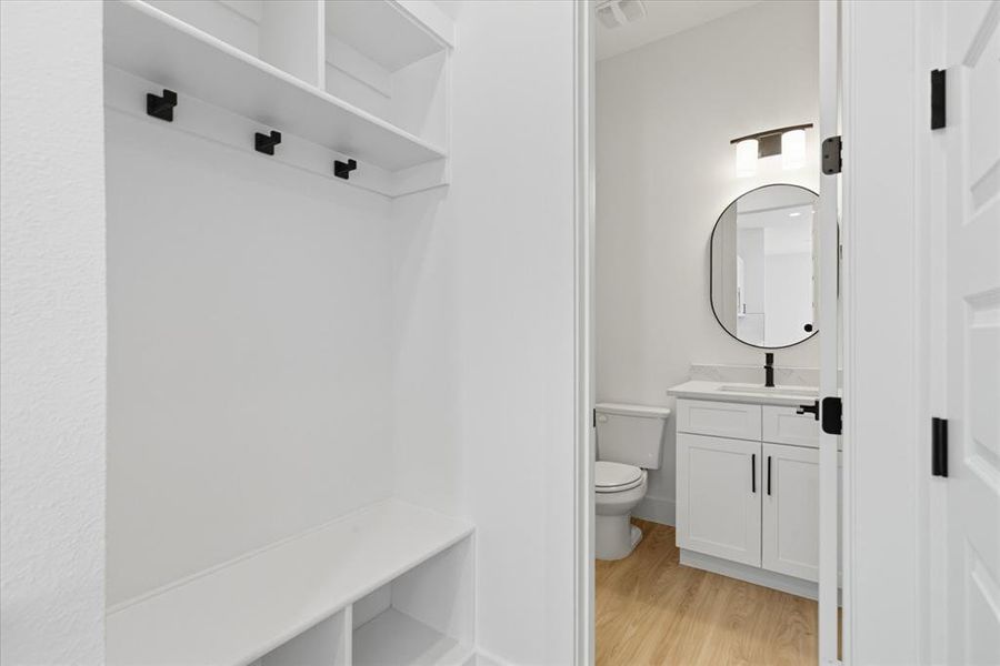 Half bathroom with light wood-type flooring and vanity
