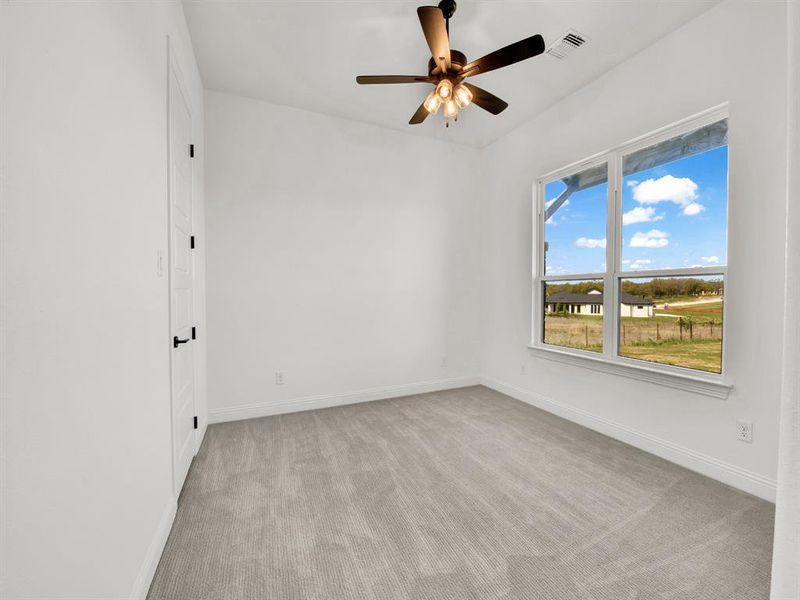 Empty room with light carpet, baseboards, a ceiling fan, and visible vents Empty room with light carpet, baseboards, a ceiling fan, and visible vents