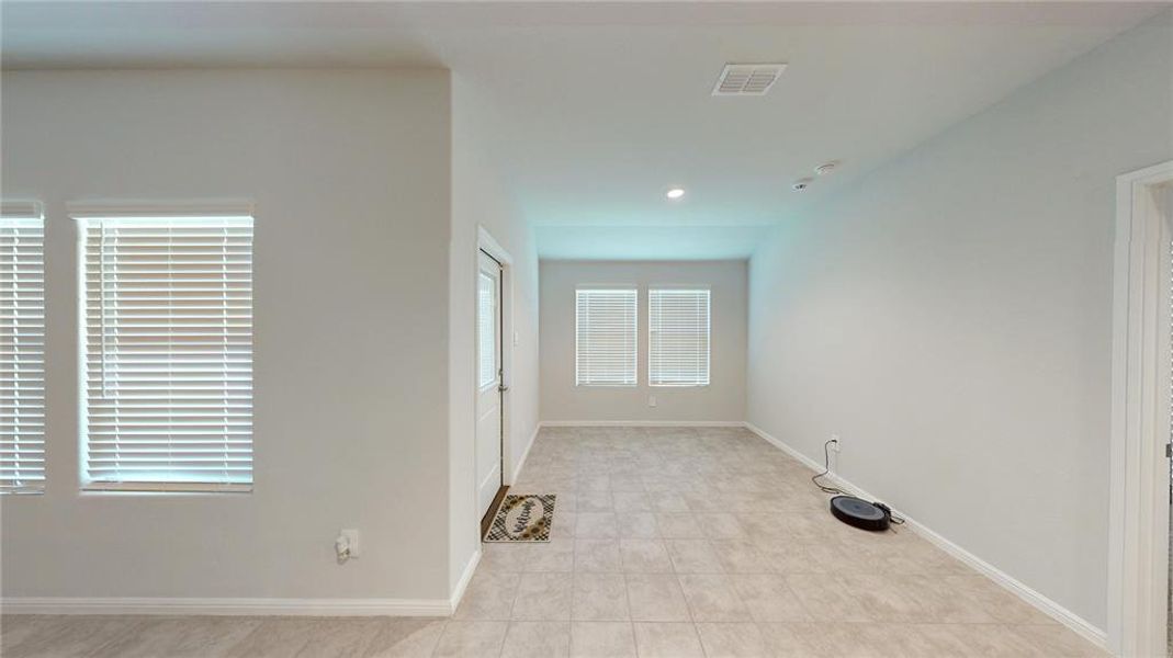 Spacious interior room featuring light-toned tile flooring throughout, multiple windows with blinds, recessed lighting, and a neutral wall palette