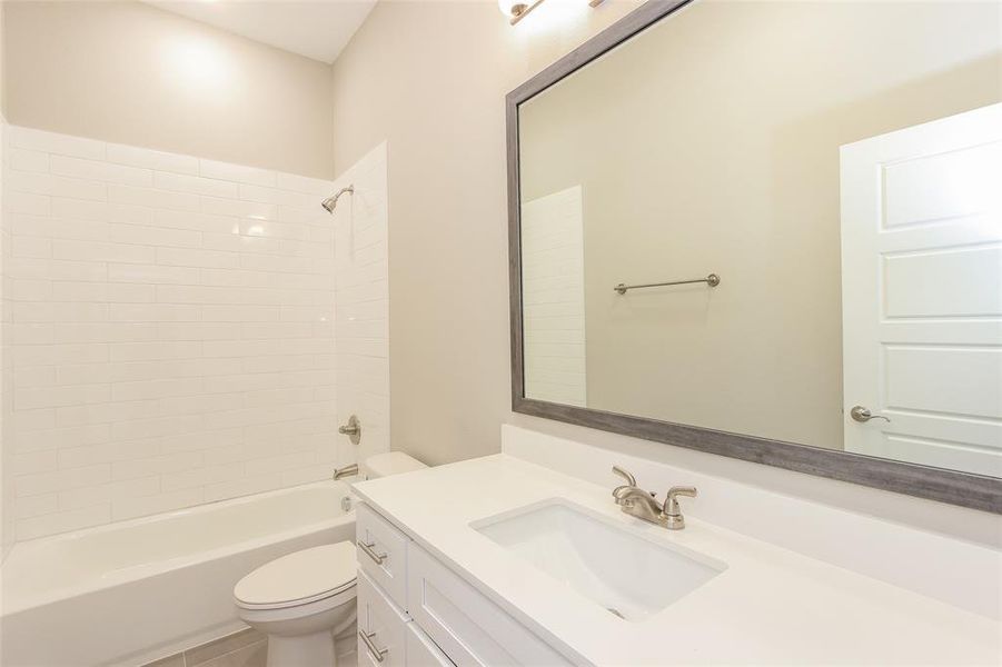 Full bathroom with vanity, tiled shower / bath combo, and toilet