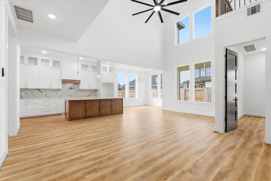 A stunning open-concept great room showcases a well-designed layout with the kitchen, dining, and living areas flowing together, abundant natural light, an oversized ceiling fan, and direct access to the first-floor primary suite.