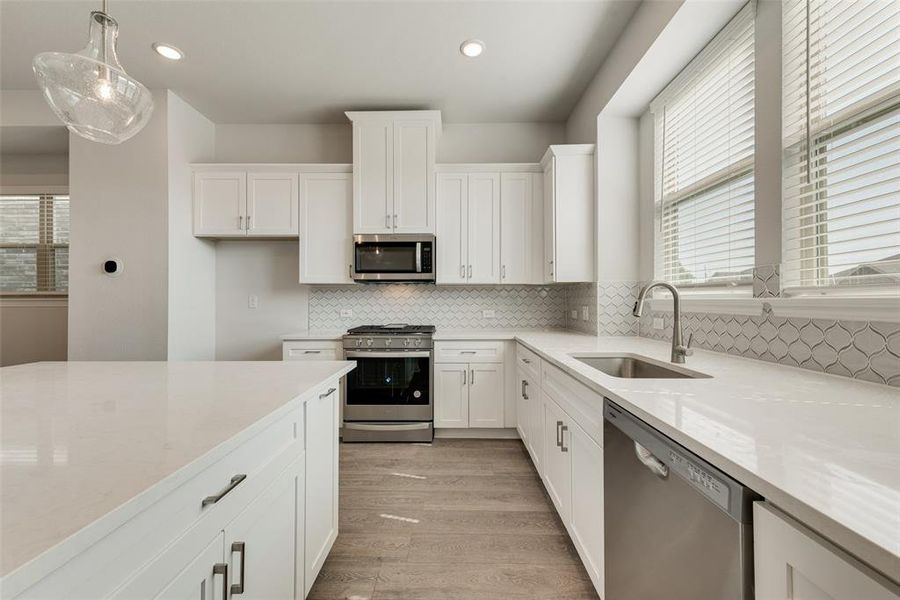 Kitchen with sink, appliances with stainless steel finishes, tasteful backsplash, and a wealth of natural light