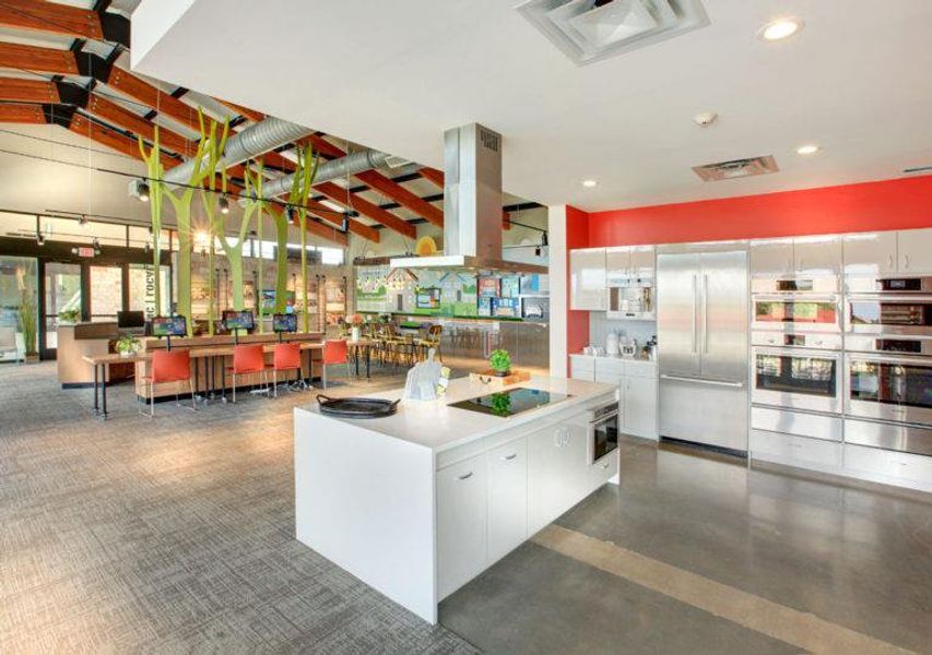 Kitchen with white cabinetry, modern cabinets, stainless steel appliances, island exhaust hood, and light countertops Kitchen with white cabinetry, modern cabinets, stainless steel appliances, island exhaust hood, and light countertops