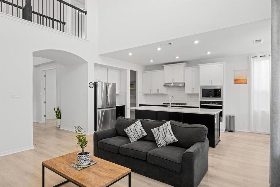 Living area with arched walkways, light wood-style floors, a towering ceiling, recessed lighting, and radiator Living area with arched walkways, light wood-style floors, a towering ceiling, recessed lighting, and radiator