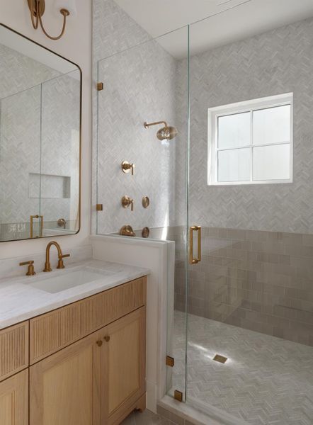 Large frameless glass primary shower features multi valve body sprays and hand held.