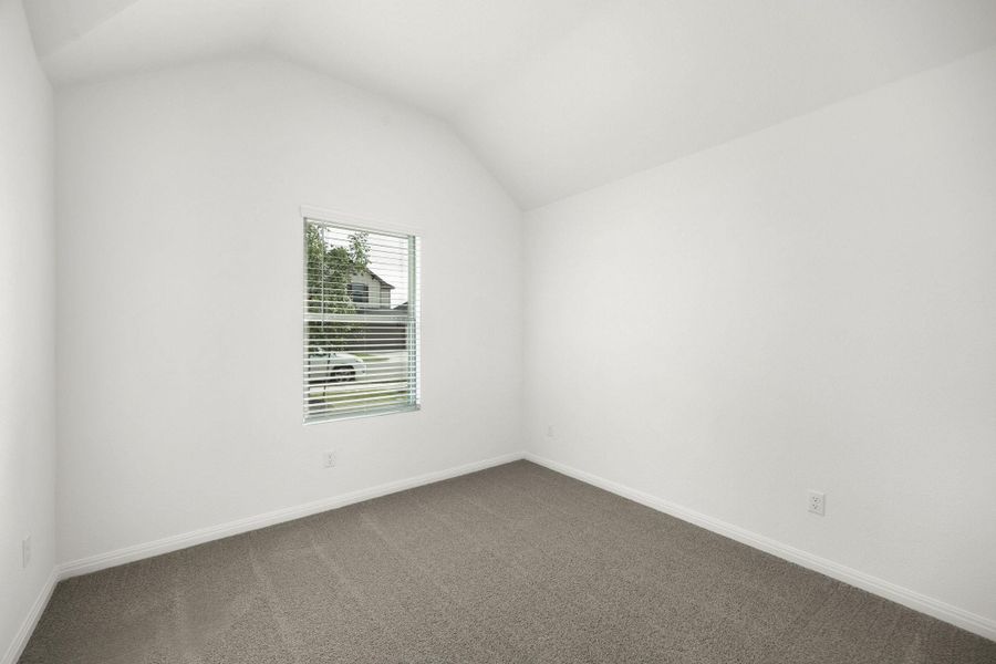 Empty room with lofted ceiling and dark carpet