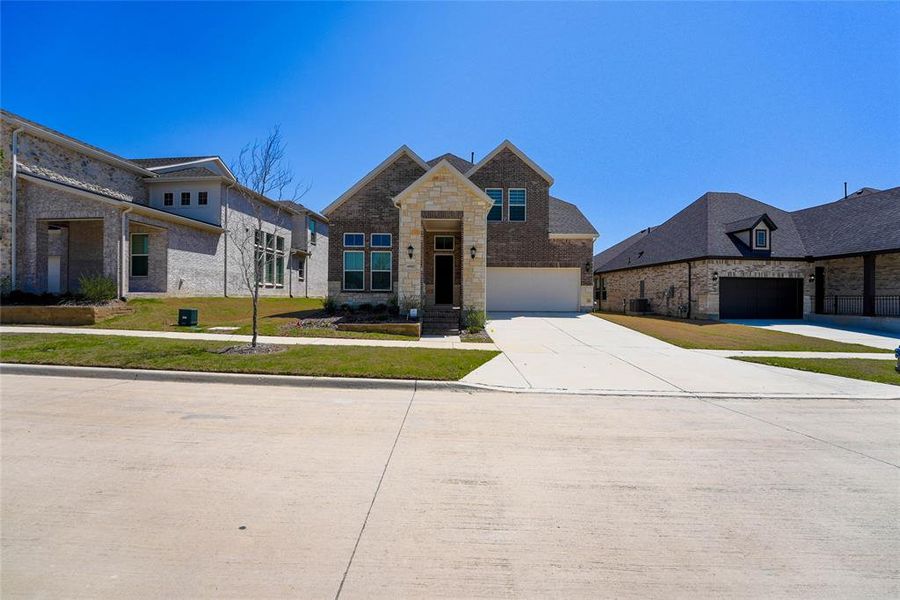 View of front of property featuring a front yard, driveway, and stone siding