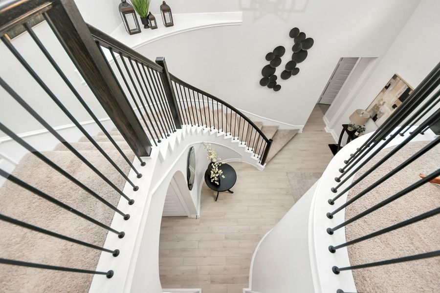 Elegant curved staircase with iron balusters overlooking the foyer.