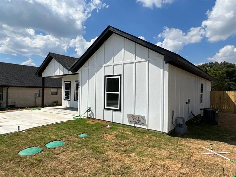 Front view of property featuring a patio area, a yard, and cooling unit