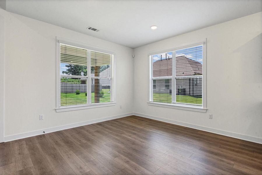 Spacious room featuring wood-finish flooring, two large windows with blinds, recessed lighting, and crisp white walls Spacious room featuring wood-finish flooring, two large windows with blinds, recessed lighting, and crisp white walls