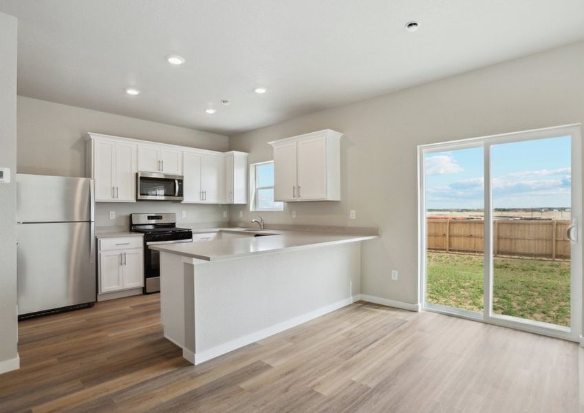 The kitchen has stainless steel appliances and plank flooring.