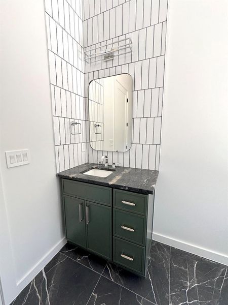 Bathroom featuring baseboards, tile walls, marble finish floor, and vanity