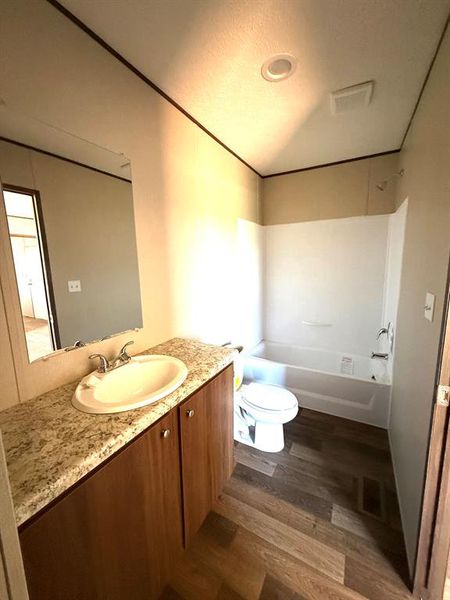 Bathroom featuring a wood-finish vanity with a light speckled countertop, an oval undermount sink, and a chrome faucet Bathroom featuring a wood-finish vanity with a light speckled countertop, an oval undermount sink, and a chrome faucet