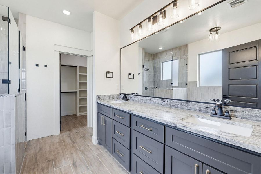Marble countertops and a large walk-in shower elevate this contemporary primary bathroom. Marble countertops and a large walk-in shower elevate this contemporary primary bathroom.
