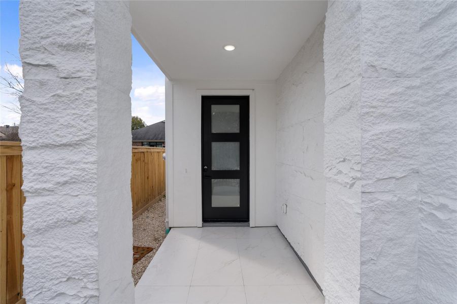 Covered front entry with modern black door and sleek architectural detailing.