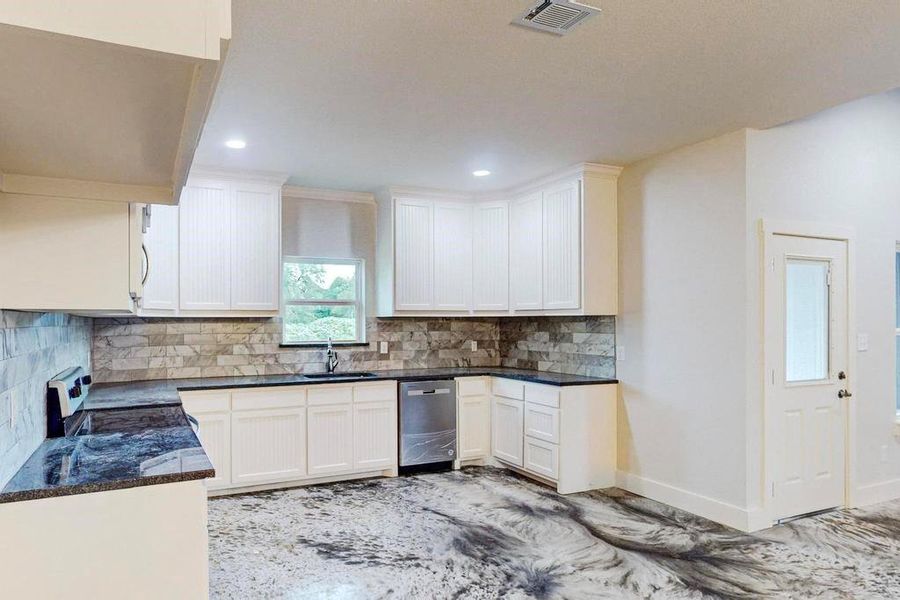 Kitchen with white cabinetry, sink, stainless steel dishwasher, decorative backsplash, and range