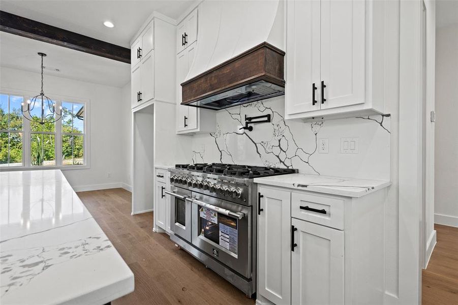 Kitchen featuring range with two ovens, light stone countertops, premium range hood, white cabinets, and dark wood-type flooring Kitchen featuring range with two ovens, light stone countertops, premium range hood, white cabinets, and dark wood-type flooring