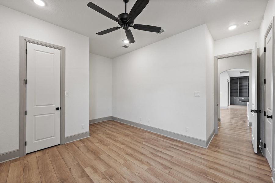 Spare room with visible vents, baseboards, arched walkways, ceiling fan, and light wood-style floors