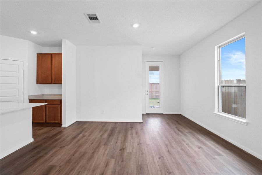 Start your day with a warm cup of coffee and quality time in this charming dining area! Highlights include a large window, custom neutral paint, vinyl plank flooring, recessed lighting, high ceilings, and a convenient door leading to the rear patio and backyard.