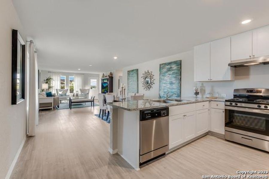 Kitchen featuring stainless steel appliances, recessed lighting, white cabinets, a peninsula, and light wood-style floors Kitchen featuring stainless steel appliances, recessed lighting, white cabinets, a peninsula, and light wood-style floors