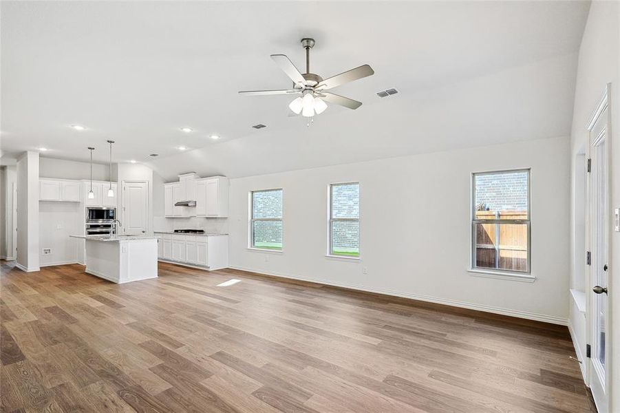 Unfurnished living room with ceiling fan, light hardwood / wood-style flooring, lofted ceiling, and a wealth of natural light