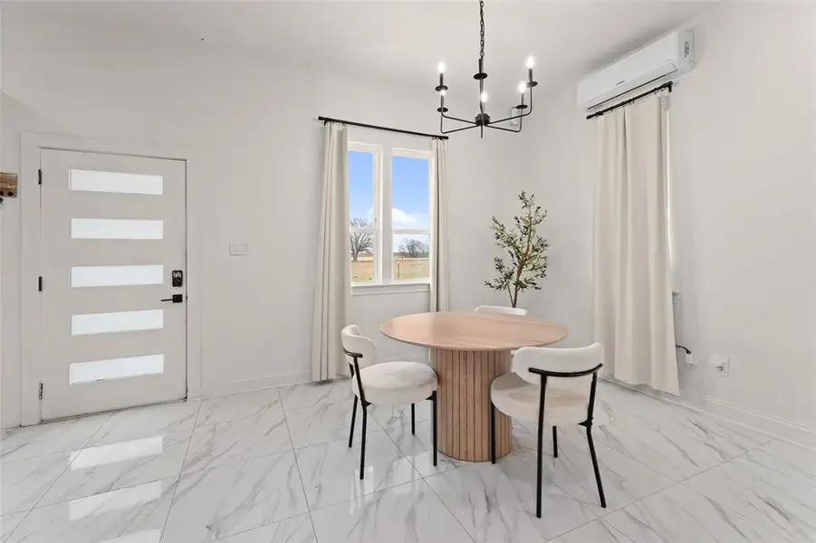 Dining area with light marble finish flooring, a wall mounted AC, and a chandelier