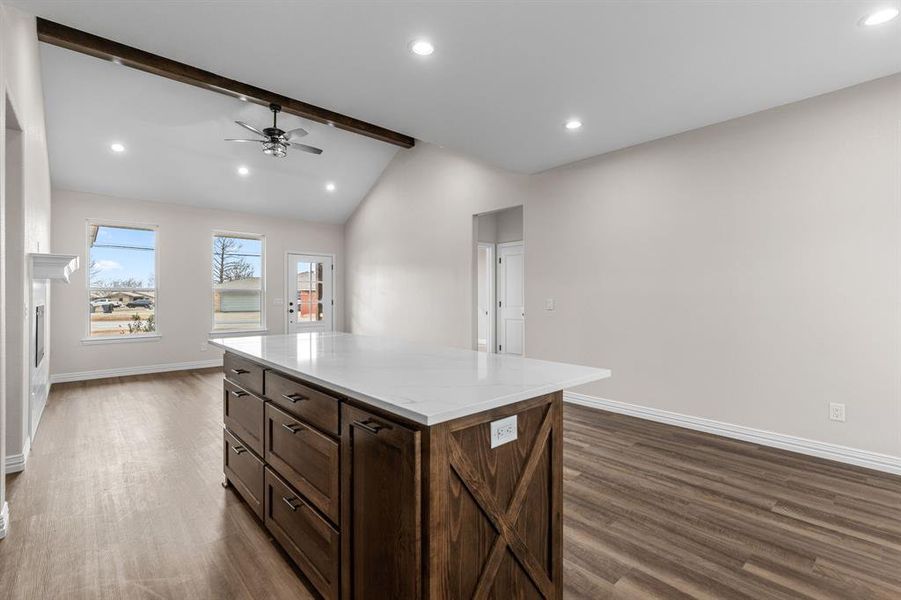 Kitchen featuring dark wood-type flooring, ceiling fan, a kitchen island, and vaulted ceiling with beams Kitchen featuring dark wood-type flooring, ceiling fan, a kitchen island, and vaulted ceiling with beams