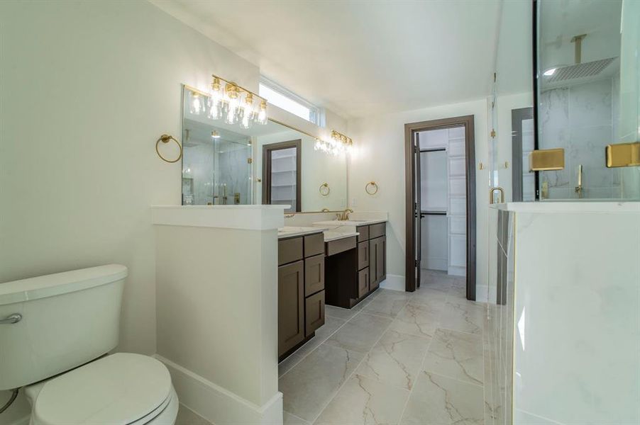 Full bathroom with light marble finish flooring, double vanity, a stall shower, and a walk in closet Full bathroom with light marble finish flooring, double vanity, a stall shower, and a walk in closet