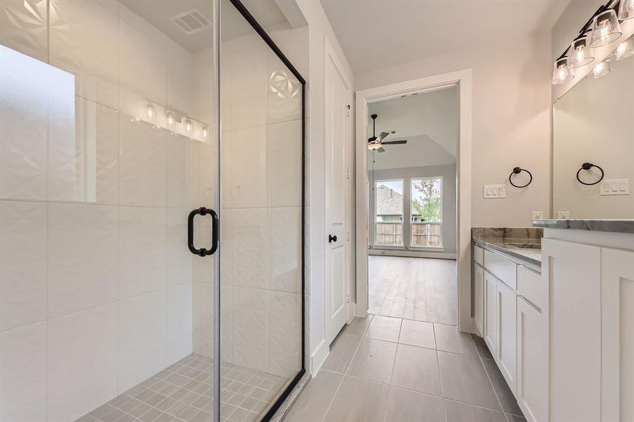 Full bathroom featuring vanity, tile patterned flooring, a stall shower, and a ceiling fan