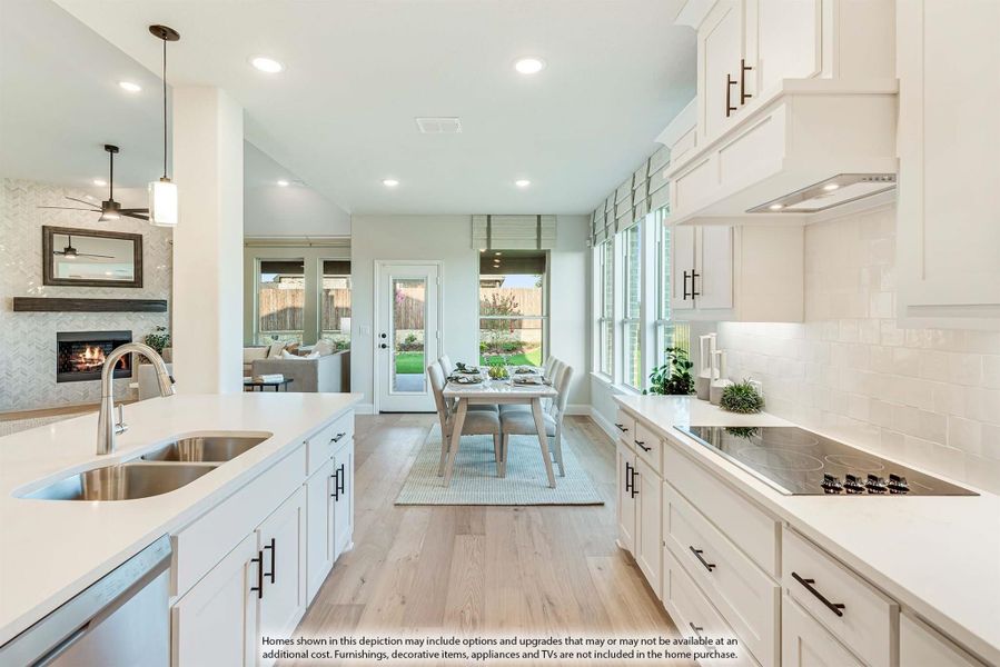 Open kitchen with white cabinets, quartz countertops, and island sink, overlooking dining area and living room with fireplace.