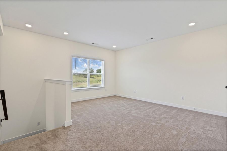 Spacious room featuring neutral carpet flooring, recessed lighting, and a large window with white blinds Spacious room featuring neutral carpet flooring, recessed lighting, and a large window with white blinds