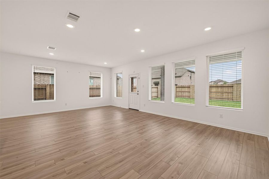 Spacious living area featuring upgraded flooring, upgraded semi-gloss paint, and abundant natural light throughout the open-concept design.