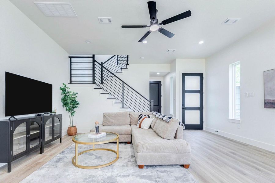 The main level features a striking modern staircase with black horizontal metal railings and a frosted-glass accent door.