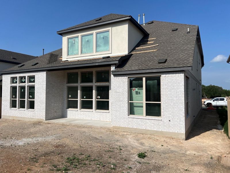 Back of property featuring roof with shingles and brick siding