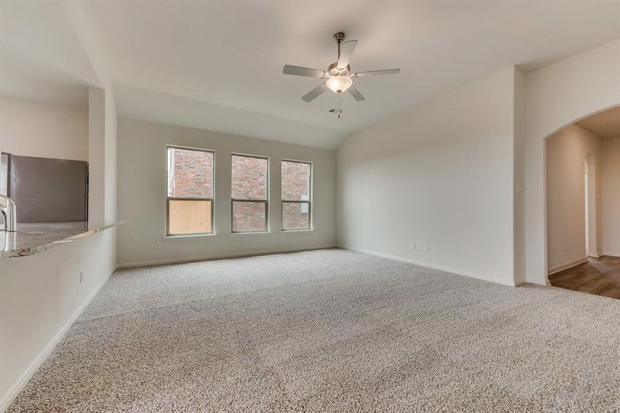 Carpeted spare room with vaulted ceiling and ceiling fan