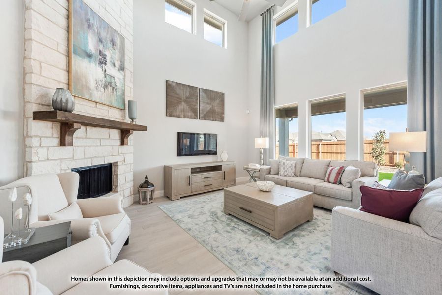 Living room with two-story ceiling, stone fireplace, large windows, and neutral furniture seating area