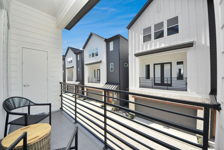 This cozy balcony offers a serene outdoor space with sleek railings, two chairs, and a small table—ideal for enjoying morning coffee or evening relaxation while taking in the neighborhood views.